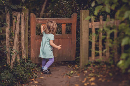 Young girl closing the wooden gates in the gardenの写真素材