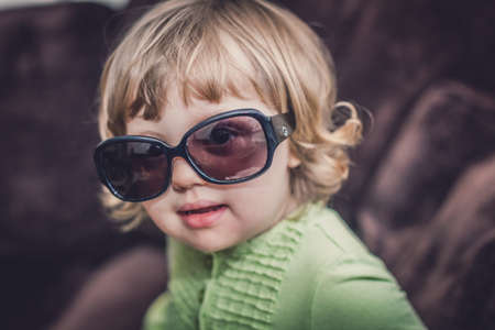 Portrait of a cute little baby girl wearing large dark designer glassesの写真素材