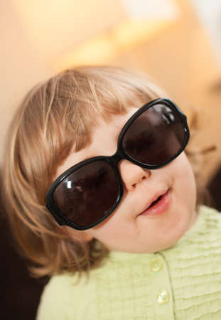 Portrait of a cute little baby girl wearing large dark designer glassesの写真素材