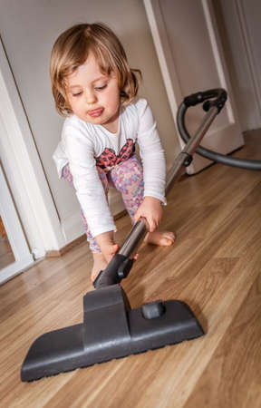 Little girl using the vacuum cleaner for the first timeの写真素材