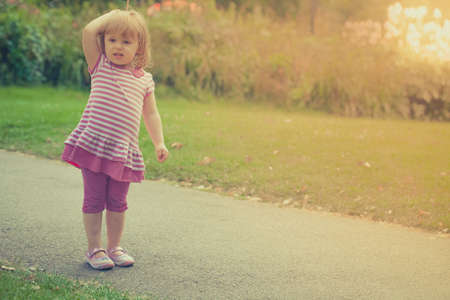 Little girl standing on a path in a park wondering where mummy went and where to goの写真素材