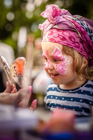 Little girl having her face painted during local fairの写真素材