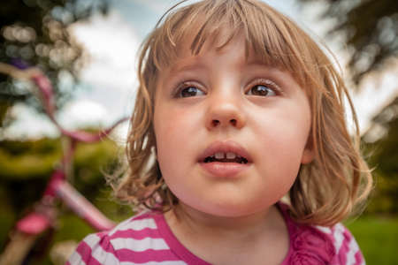 Outdoor portrait of a cute little girl with her bike in the backgroundの写真素材