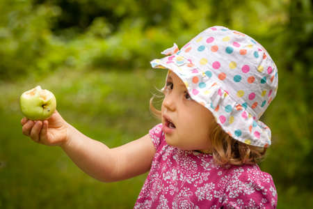 Cute little girl holding half eaten appleの写真素材