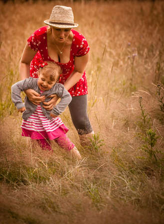 Mother and daughter playing together on a meadowの写真素材