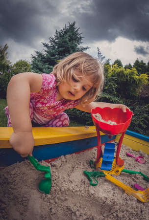 Girl playing in the sandpit in the home gardenの写真素材