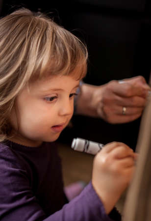 Little girl drawing on a cardboard at homeの写真素材
