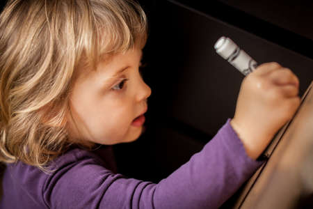 Little girl drawing on a cardboard at homeの写真素材