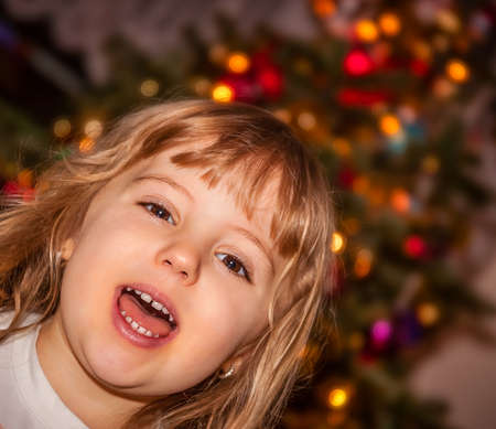 Cute Christmas girl with the Christmas tree in the backgroundの写真素材