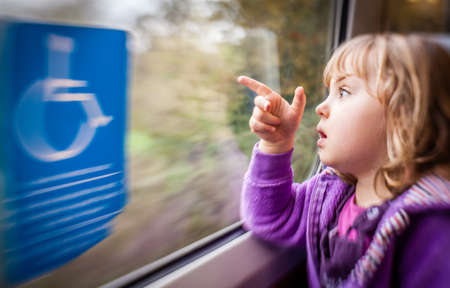 Little girl sitting inside the train carriage and pointing outside