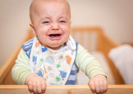 Little boy, infant, standing in his bed and crying loudlyの写真素材