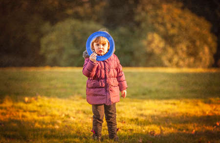 Little girl throwing flying disc in the park in autumnの写真素材