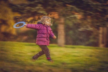 Little girl throwing flying disc in the park in autumnの写真素材