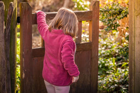 Young girl opening the wooden gates in the gardenの写真素材