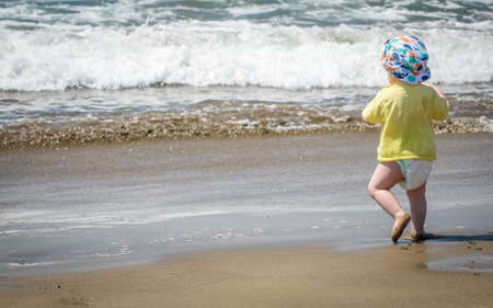 Little boy running towards the sea on holidayの写真素材