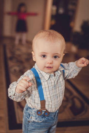 Portrait of a cute little baby boy standing in a living room at homeの写真素材