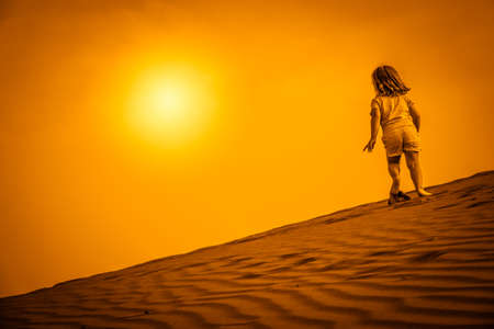 Little girl walking up the sand on the sand dunes in  the Natural Reserve of Dunes of Maspaloma in Gran Canariaの写真素材