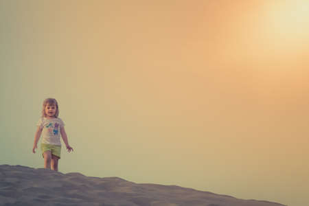 Little girl standing on top of the sand dunes in  the Natural Reserve of Dunes of Maspalomas in Gran Canariaの写真素材