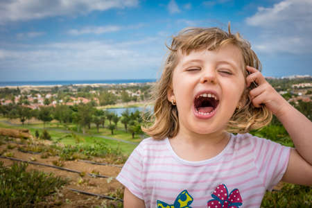 Little girl standing on a viewpoint over Maspalomas in gran Canaria and shouting loudlyの写真素材