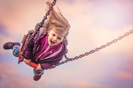 Young girl having fun on a sling in a playgroundの写真素材
