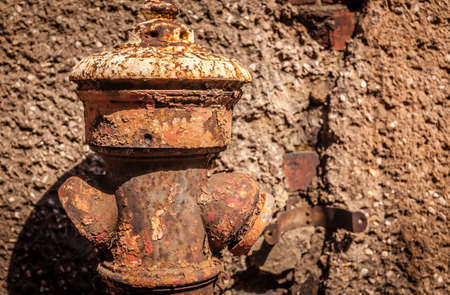 Disused and rusted old hydrant in front of a old homeの写真素材