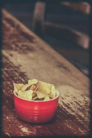 Nachos in red bowl on a table in a pubの写真素材