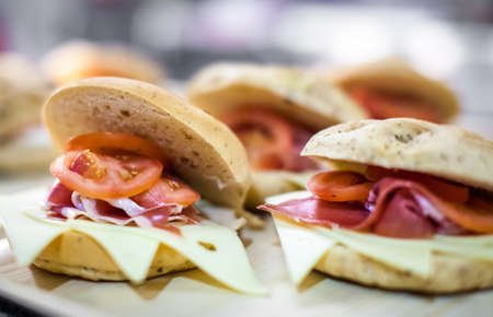 Breakfast buns on a plate, filled with cheddar cheese, prosciutto ham and tomatoesの写真素材