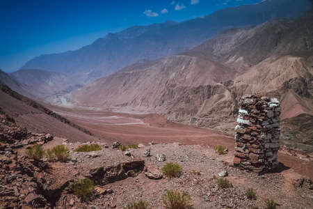 Stone marker on a cliff above the mountain valley with Hunza river flowing below, Karakorum, Pakistanの写真素材