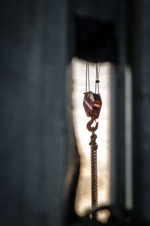 Heavy duty crane with top cable pulley and hook photographed at sunset