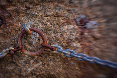 Old rusted chain attached to the stone wall in the portの写真素材
