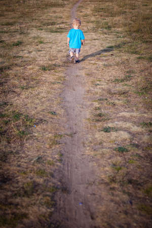 Little boy walking on a narrow path in the countrysideの写真素材