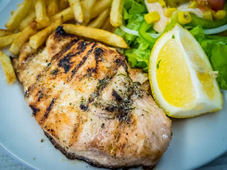 Grilled chicken breast meal served with summer salad and chips