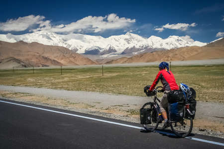 Woman cyclist on stunning KKH road through Karakorum mountains in southern Chinaの写真素材