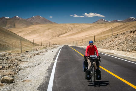 Woman cyclist on stunning KKH road through Karakorum mountains in southern Chinaの写真素材