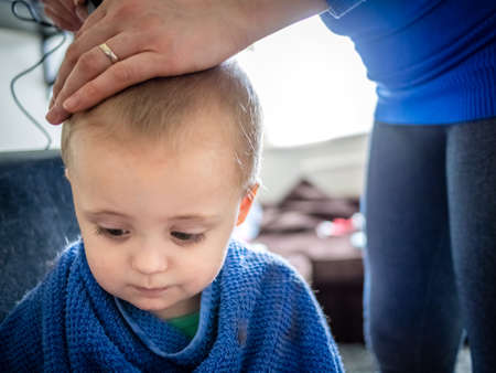 Mother cutting hair of her little sonの写真素材