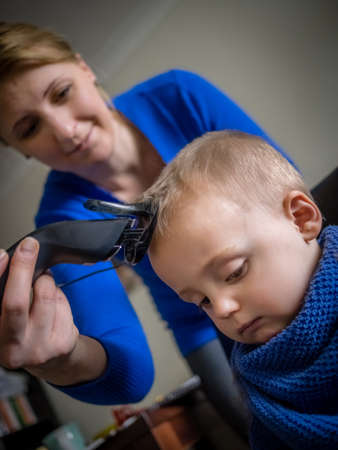 Mother cutting hair of her little sonの写真素材