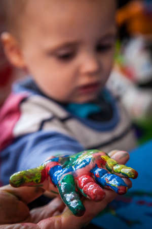 Child's hand with colored fingers from using paintの写真素材
