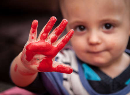 Child's hand with colored fingers from using paintの写真素材