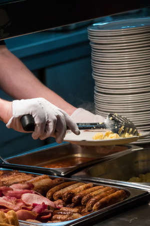 Hands of a person serving breakfast in a hotel restaurantの写真素材
