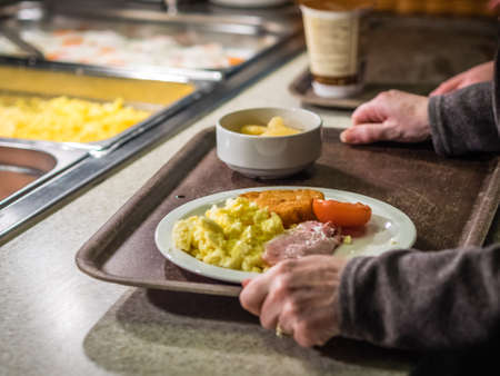 Man holding tray with a breakfast being collected from a breakfast counter in a restaurant in a hotelの写真素材
