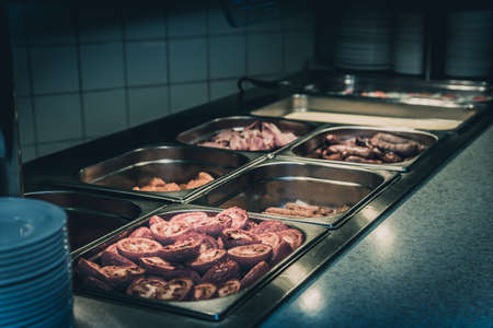 Hot counter containing warm breakfast items such as scrambled or fried eggs, bacon, sausages and others in a self service restaurant in a hotelの写真素材