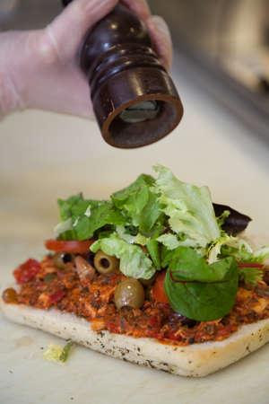 Close up of a person hands preparing chicken, lettuce and tomato sandwich in a cafeteria