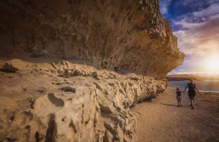 Mother and daughter walking together on a sandy pathway along the rocky coastline in Ajuy, Parque Rural de Betancuria in Fuerteventura, Canary Island, Spainの写真素材