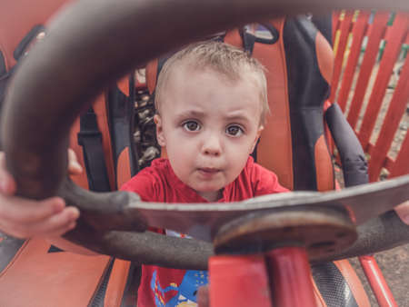 Little boy sitting behind the wheel of an immobile car truck in a playgroundの写真素材