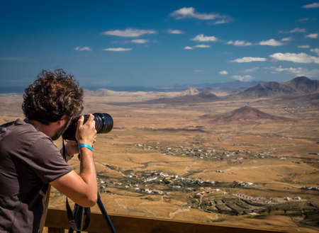 Man taking pictures of a Fuerteventura landscape from the viewing platform of the Morro Velosa viewpoint, Fuerteventura,  Canary Islands, Spain. Picture taken 13 April 2016のeditorial素材