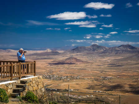 Man taking pictures of a Fuerteventura landscape from the viewing platform of the Morro Velosa viewpoint, Fuerteventura,  Canary Islands, Spain. Picture taken 13 April 2016のeditorial素材