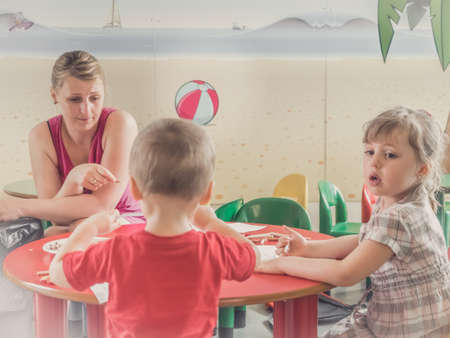 Woman and children drawing and coloring pictures during art time at the nurseryの写真素材