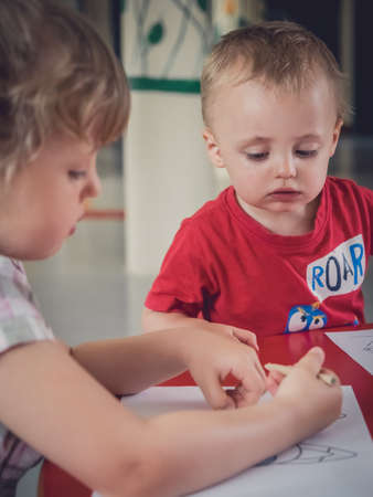 Little kids colouring pictures during art time at the nurseryの写真素材
