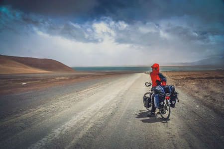 Solo female cyclist on the bicycle in the stunning remote part of Western Tibetの写真素材