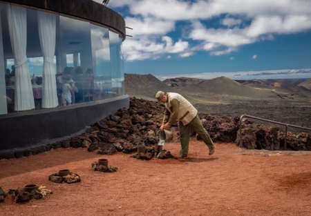 Lanzarote, Spain -  August 23, 2016: Man putting water into a steaming volcanic hole creating geyser, Timanfaya National Park, Lanzarote, Canary Islands, Spainのeditorial素材